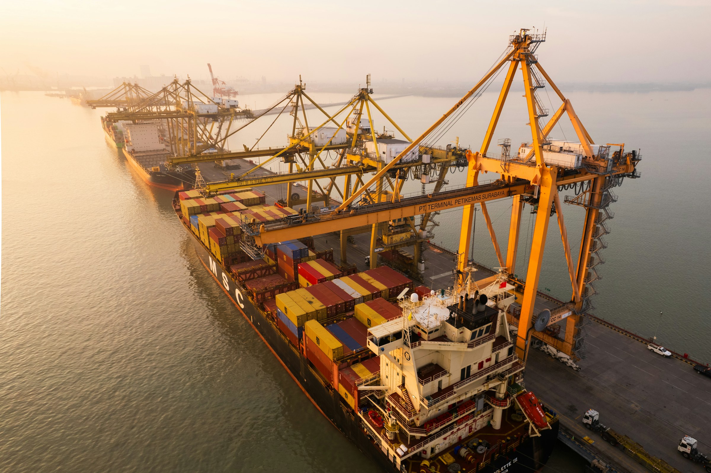 A container vessel being loaded by cranes at a busy port terminal